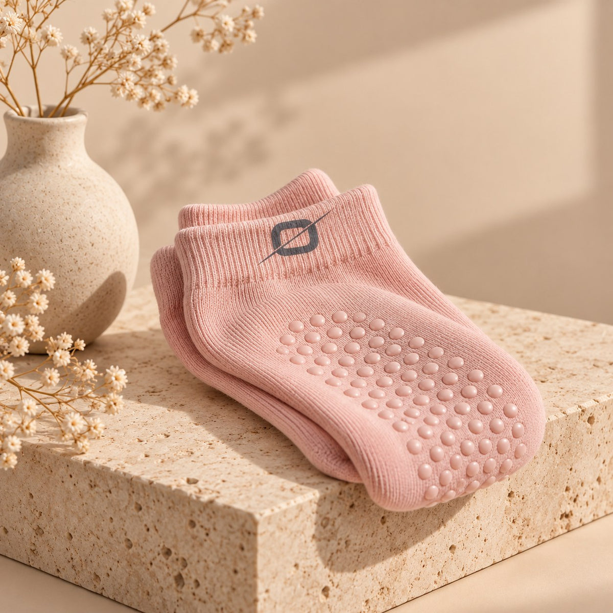 Roze ORION Grip Socks gevouwen op een stenen sokkel