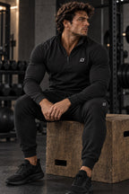 Man in de zwarte ORION Zip Set zit op een plyo box